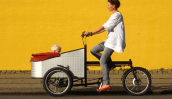 Cargo bike being ridden in front of an orange wall